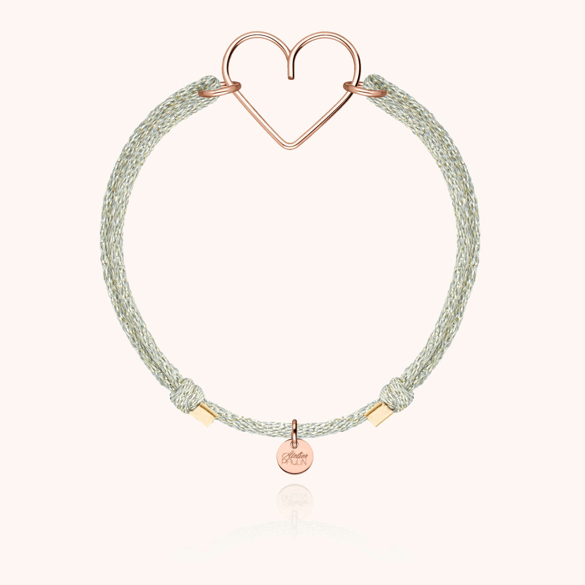 Primo piano del cordino in seta lurex e del cuore in filo d'oro rosa laminato 14k