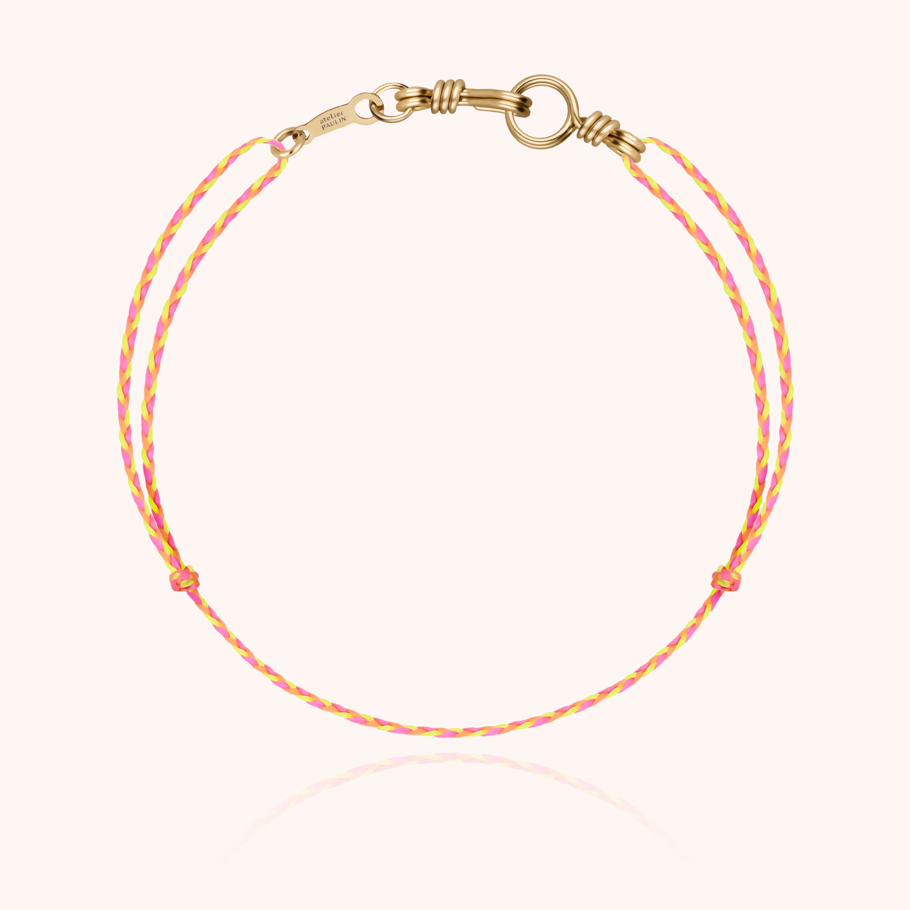 Main portant le bracelet or jaune laminé avec cordon noir satiné