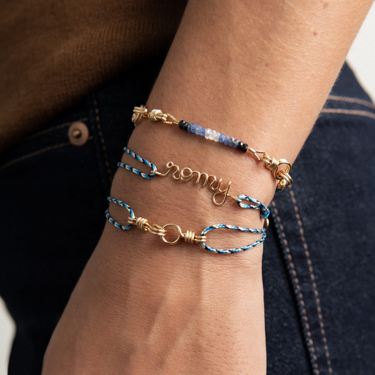Dettaglio dello zaffiro blu e del filo d'oro modellato a mano sul bracciale in cordino