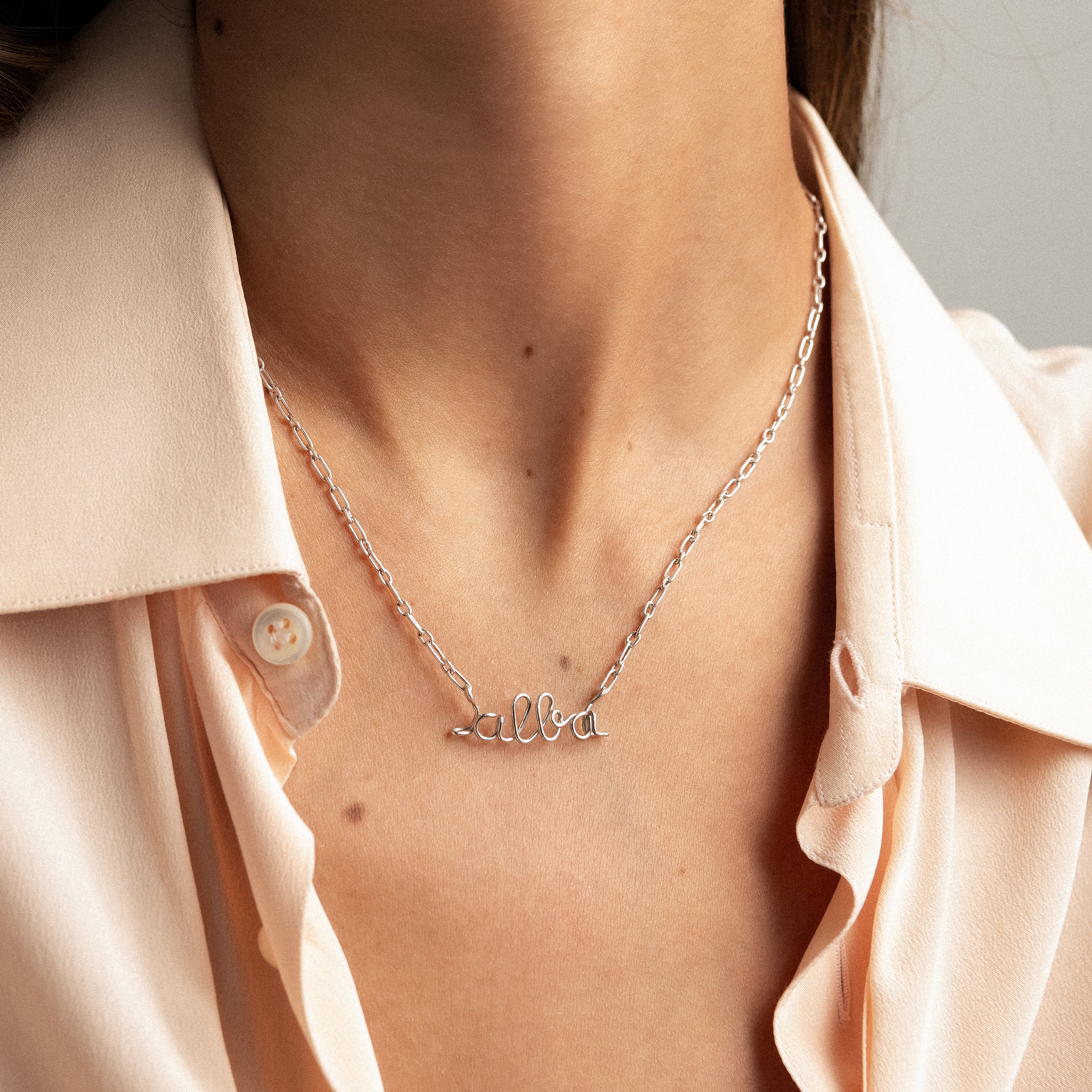 Détail du façonnage à la main des lettres en fil d'argent sterling