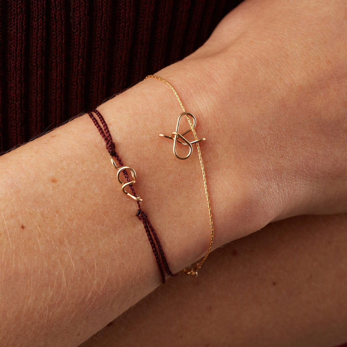 Mini Attache moi Initiale Plain Cord Bracelet with its gold initial, worn on the wrist