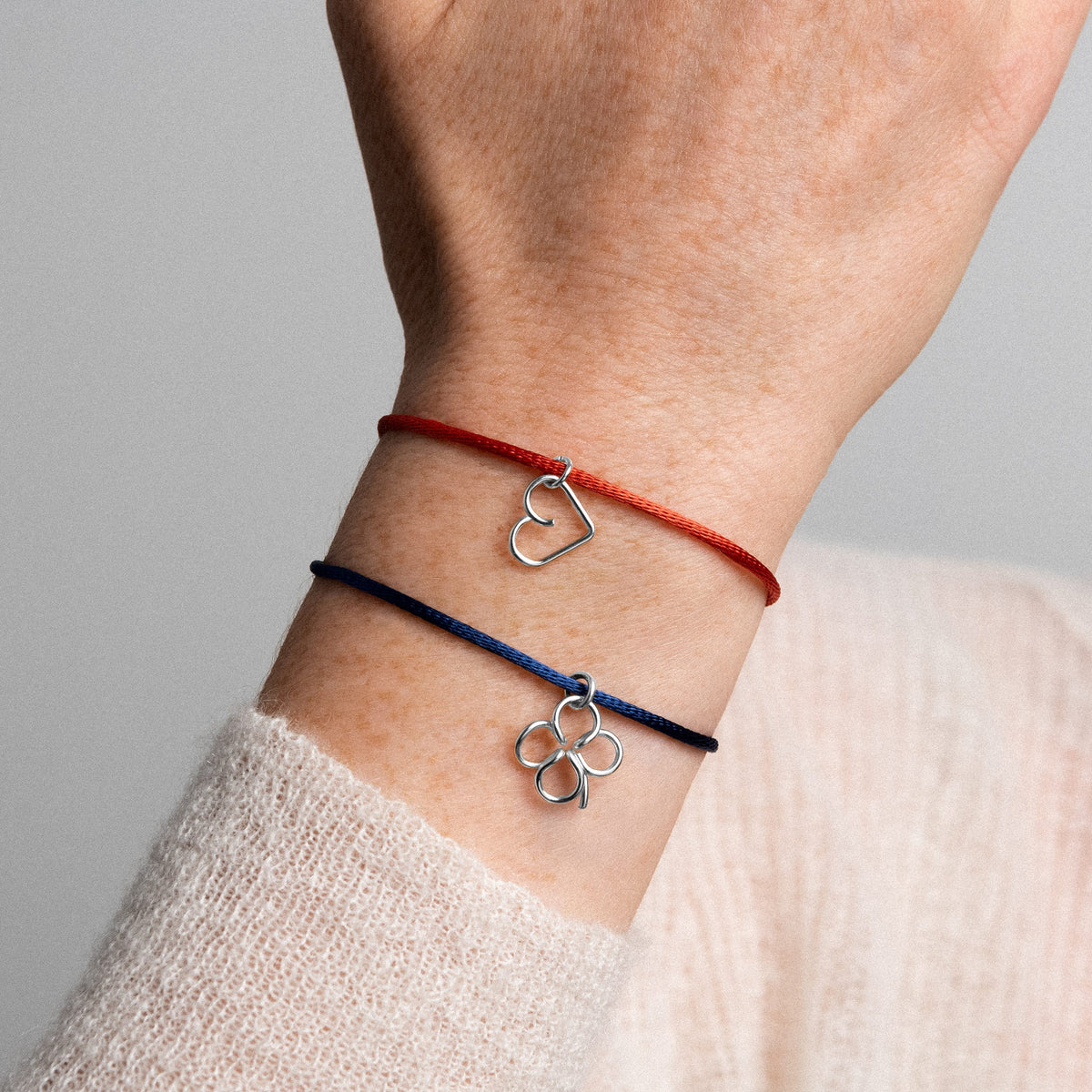 Primo piano del cordino sintetico satinato e del charm in filo d'argento sterling 925
