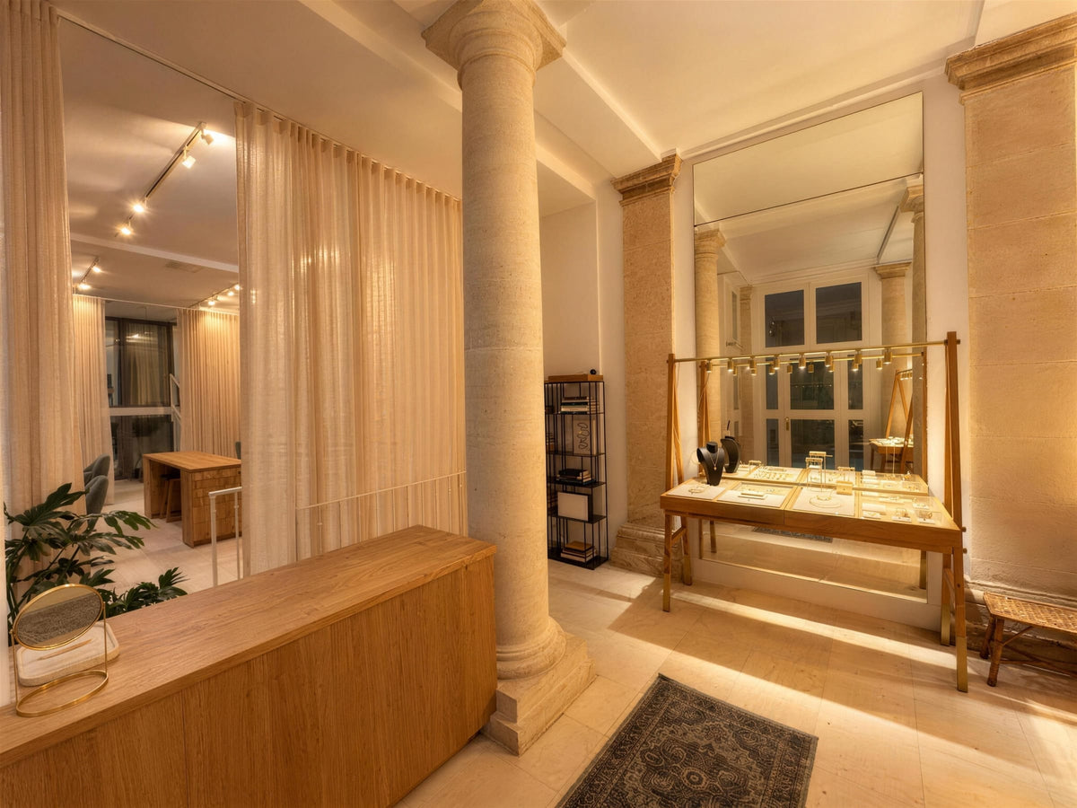 La boutique Atelier Paulin dans le Marais : une colonne de pierre et les bijoux personnalisés présentés sur une table en bois