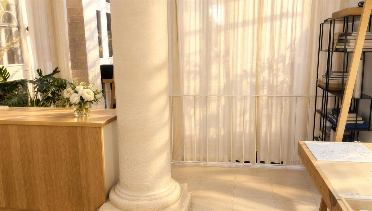 Le comptoir en bois blond de la boutique Atelier Paulin, au pied d’une colonne de pierre, baigné de lumière