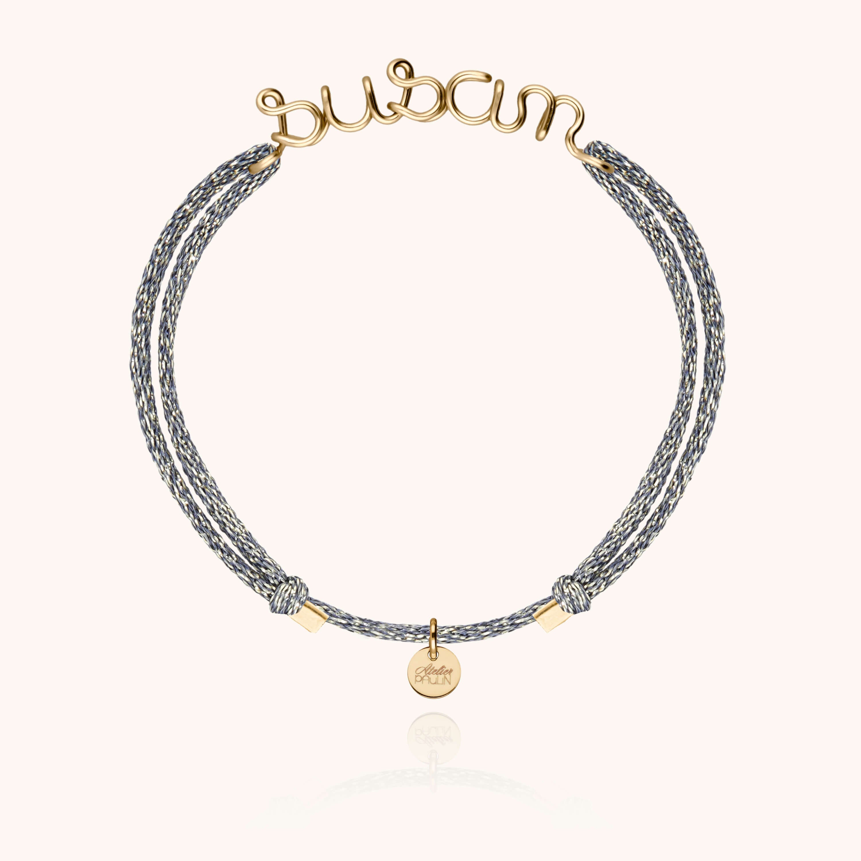 Bracelet cordon personnalisé porté au poignet montrant le prénom en or jaune