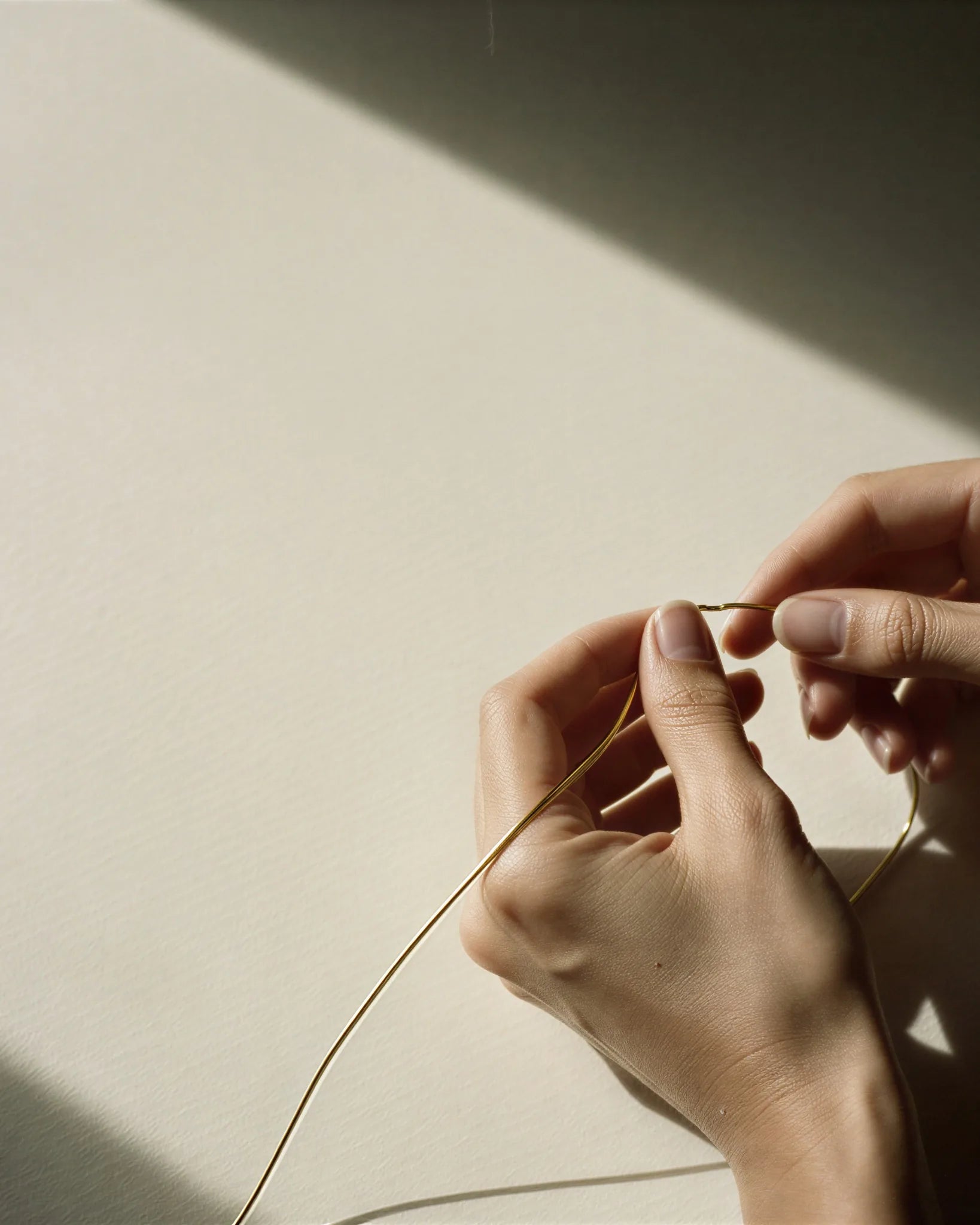 Main d'artisan qui façonne le fil précieux à l'atelier parisien