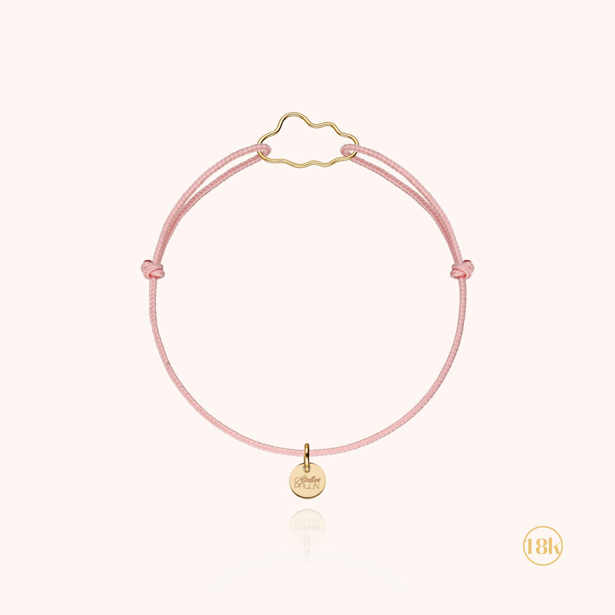 Bracciale Cordino Bambino Piccola Nuvola in filo d'oro 18kt su un cordino rosa pallido, disteso in piano