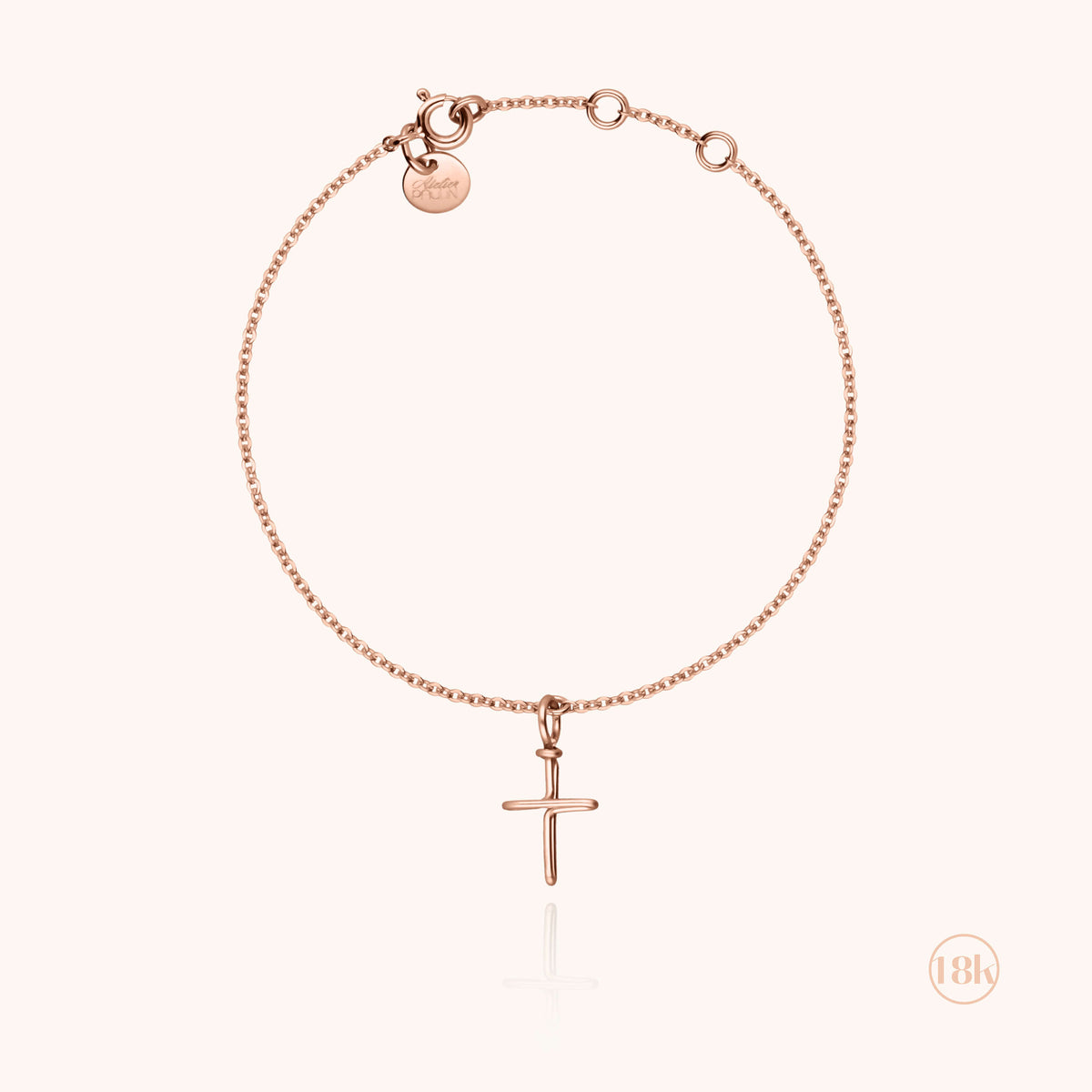 Dettaglio del charm croce in filo d'oro rosa 18kt sul bracciale