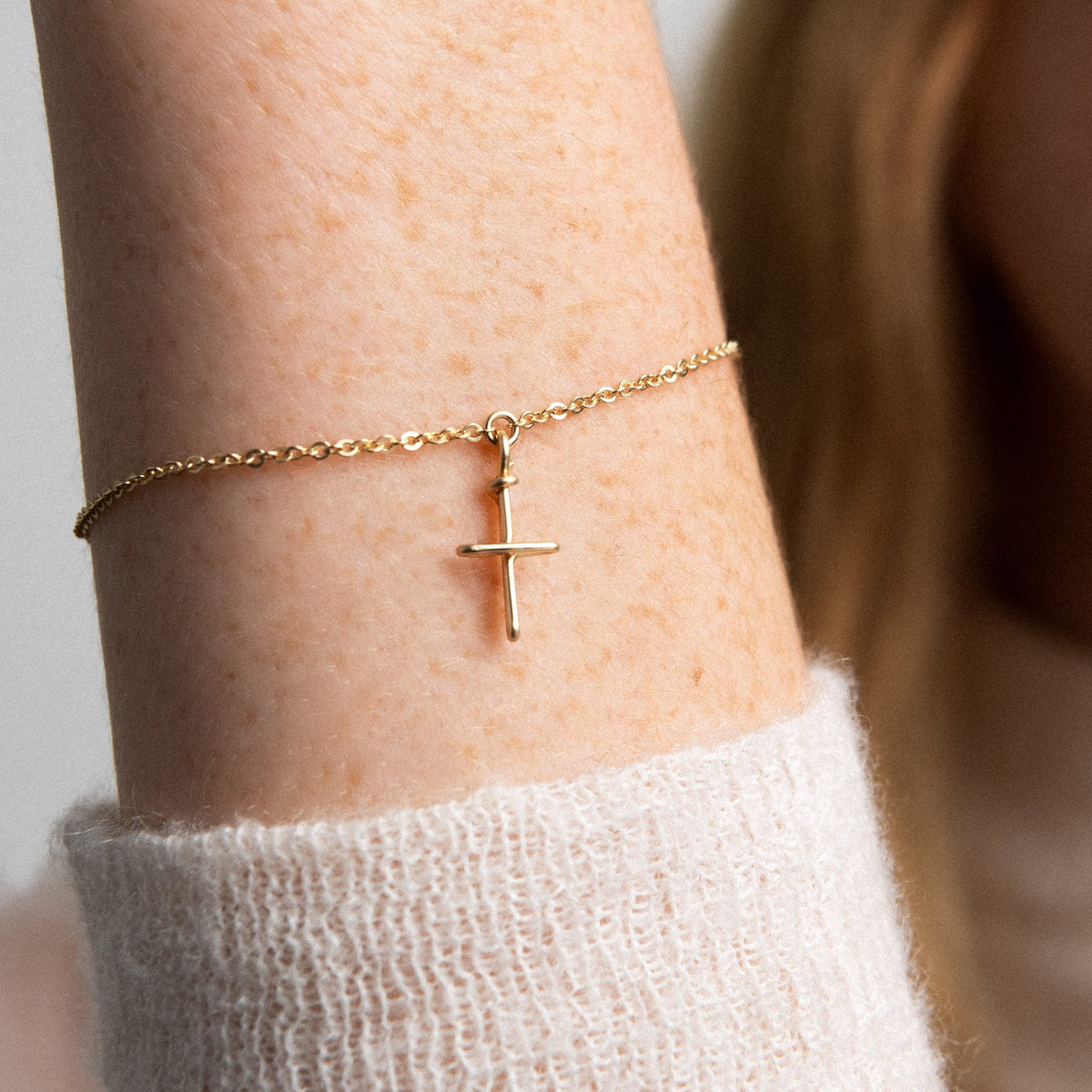 Detailansicht des von Hand geformten Kreuz-Charms am vergoldeten Armband