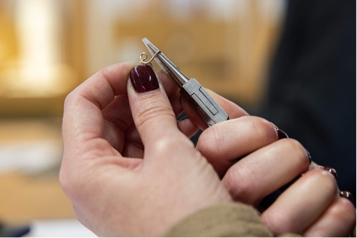 De près, une boucle de fil de métal précieux formée à la pince pendant l’atelier Au fil de l’or