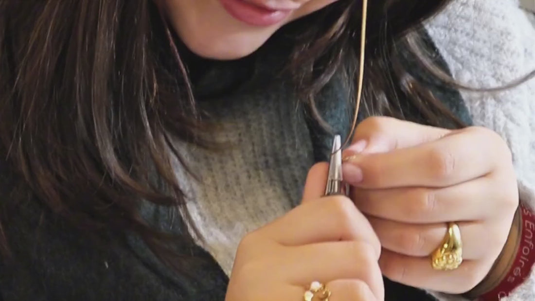 Au fil de l’or, l’atelier de création de bijoux d’Atelier Paulin à Paris : des mains façonnent un fil d’or à la pince, guidées par un artisan